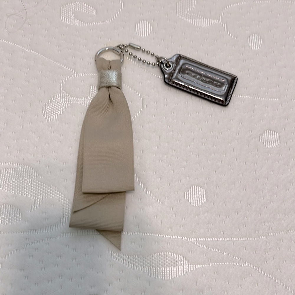 Coach hang tag, metallic bronze with tan ribbon.